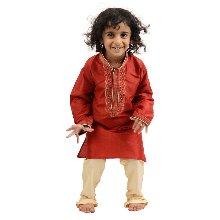 Playful pose of child in Kids Gold Kurta Set with red embroidered kurta and cream churidar, perfect for weddings and cultural celebrations.