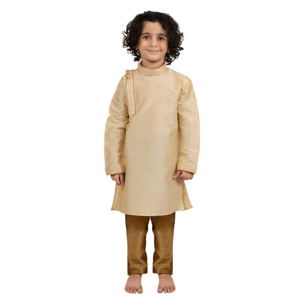 Gold Art Silk Kurta for boys with side button detail, paired with brown churidar pants. Ideal kids cotton kurta set for festive occasions.