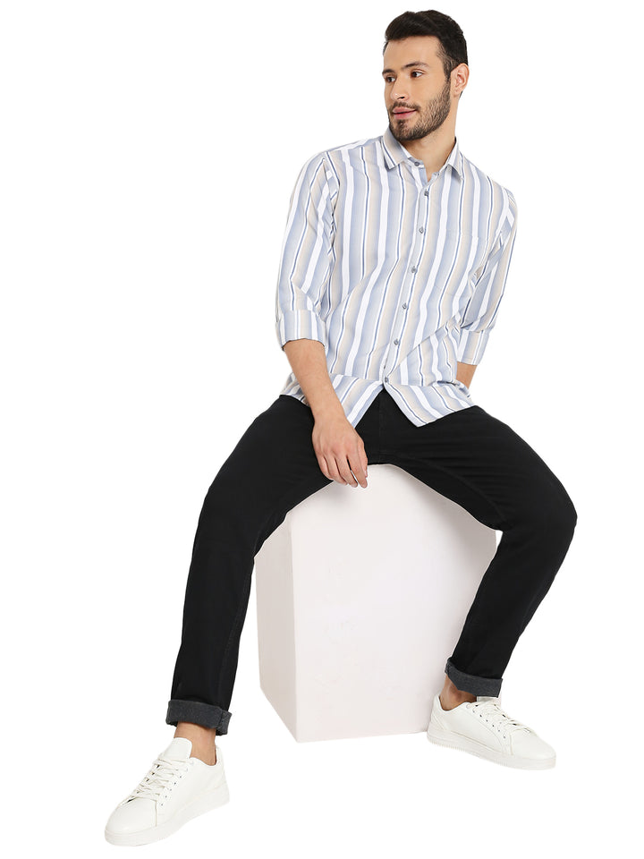 Model seated wearing Maharaja's Craft Slim Fit Striped Shirt paired with black jeans and white sneakers for a modern casual look.
