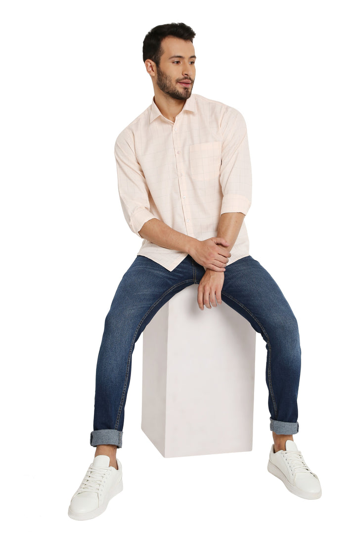 Model seated wearing Slim Fit Checkered Shirt - Orange Maharaja, paired with jeans and sneakers for a relaxed, modern look.